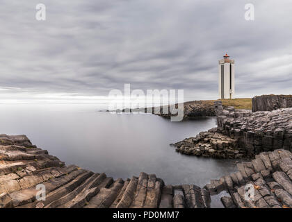 Columnar rocks or basalt columns in Iceland and the Kálfshamarsvík lighthouse near Skagaströnd on the Skagi peninsula, North Iceland Stock Photo