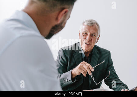 Smiling senior businessman talking with young executive in office. Business people discussing work in office. Stock Photo