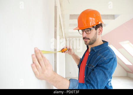 Portrait of young man using measuring tape while working on construction site. Stock Photo