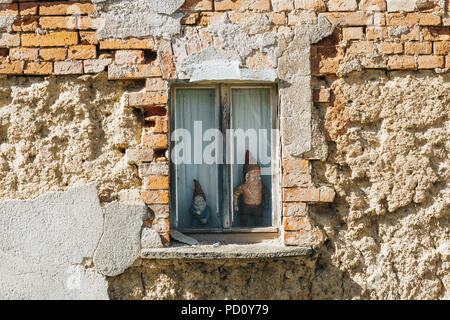 decorative garden gnomes in a window of an abandoned building in a village in Germany Stock Photo