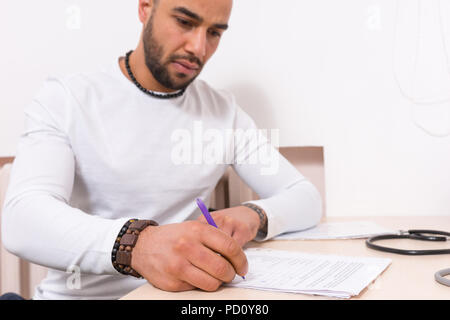 Man sitting completing a questionnaire or proof reading a report at a desk in the office in a close up cropped view Stock Photo