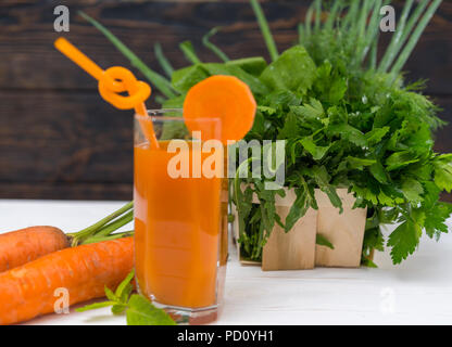 Glass of carrot and herb smoothie surrounded by fresh ingredients for a healthy breakfast beverage Stock Photo