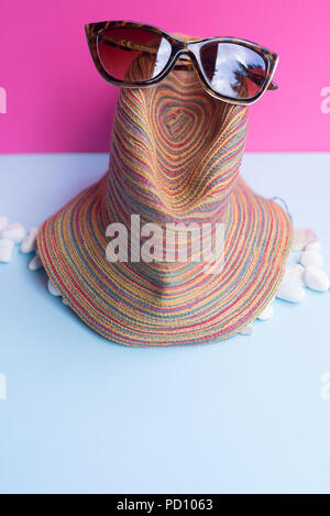 A women's sunglasses over a large sea-bream and several smaller shells on a light blue and fuchsia background. Minimalist nice image that capture the  Stock Photo