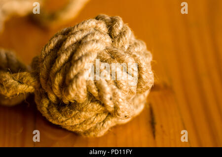 fender - marine knot of thick brown rope on a wooden background, closeup Stock Photo