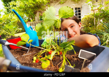 Smiling girl planting strawberries in pots Stock Photo