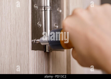 screwdriver installs door hinges Stock Photo