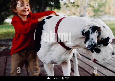 A young girl cuddles and smiles with a white and black great dane dog, Booroona walking trail on the Ross River, Rasmussen QLD 4815, Australia Stock Photo