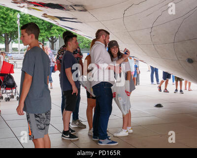 Tourists underneath the Cloud Gate sculpture in Chicago's Millennium Park. Stock Photo