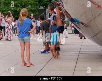 Young girl doing handstand at Cloud Gate in Chicago's Millennium Park. Stock Photo