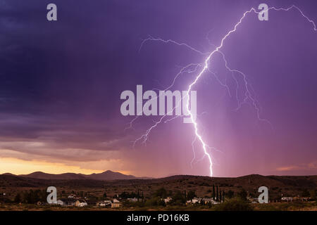 Lightning bolt striking at sunset during a monsoon thunderstorm near Mayer, Arizona Stock Photo