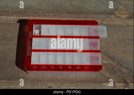 Red pill dispenser filled and partly open Stock Photo