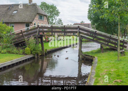 Typical wooden bridge over a canal with ducks in Giethoorn The Netherlands. Tourisitic destination, known for its picturesque canals. Stock Photo