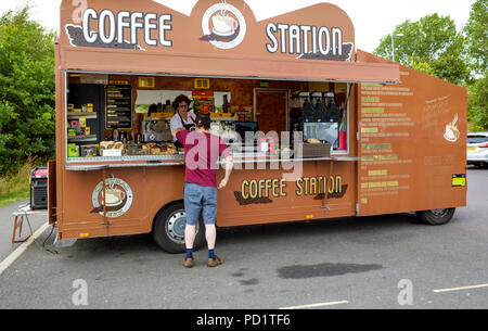 A man and a woman buying refreshments from a portable Coffee and cake ...