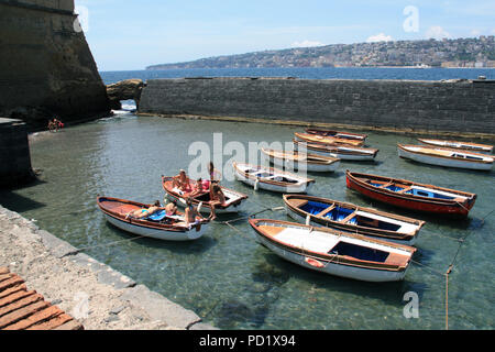 Young women and kids sunbathing on moored rowboats in a small wind protected bay next to the Castel dell'Ovo in Napoli, Italy Stock Photo