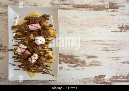 Belgian waffles with chocolate, chocolate sauce and marshmallow isolated on light wooden background. Stock Photo