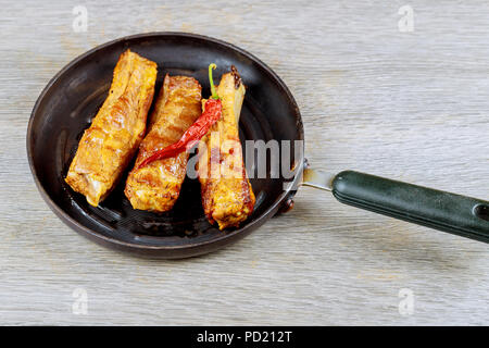 Pork ribs baked in the oven served with sauce in a frying pan, above view, close-up Stock Photo