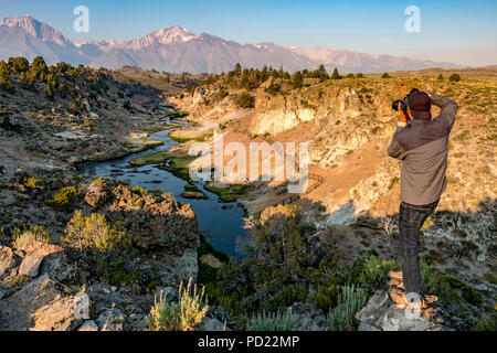 Man photographs Hot Creek in early morning at Hot Creek Geological Site near Mammoth Lakes, California. Stock Photo