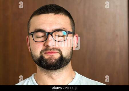 Portrait of handsome bearded black haired intelligent modern young man in glasses with short haircut and kind black eyes smiling on blurred background Stock Photo