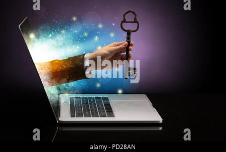 Hand with huge vintage key coming out of a laptop with sparkling effects  Stock Photo