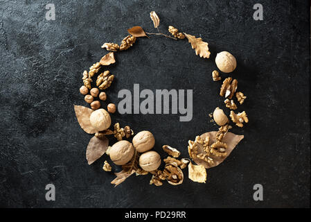 Autumn composition. Autumn Wreath with dry leaves and nuts on black background. Flat lay, top view, copy space. Stock Photo