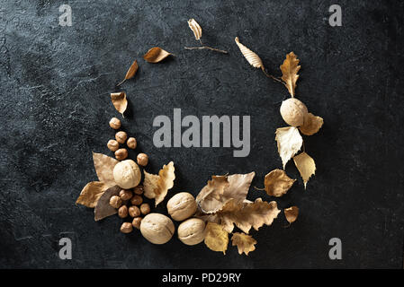 Autumn composition. Autumn Wreath with dry leaves and nuts on black background. Flat lay, top view, copy space. Stock Photo