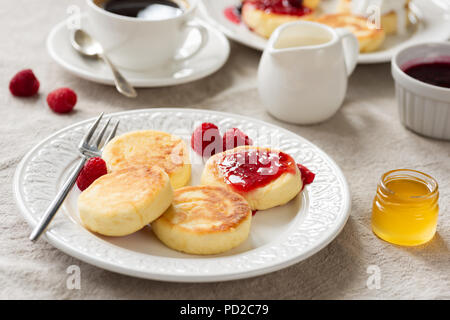 Breakfast table with cottage cheese pancakes, honey, jam and coffee. Closeup view, selective focus Stock Photo