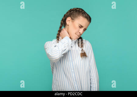 Neck pain, profile side view portrait of closed eyes sad young girl in blue striped t-shirt and pigtail hair standing and feeling pain on her neck. in Stock Photo