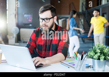 Modern Bearded Man Using Laptop in Coworking Space Stock Photo