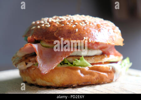 Craft burger with beacon, lettuce and vegetables on slate board. Unhealthy Junk food concept. Stock Photo
