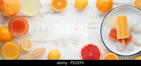 Homemade orange and lemon popsicles and citrus fruits on stone black background. Summer food concept. Stock Photo