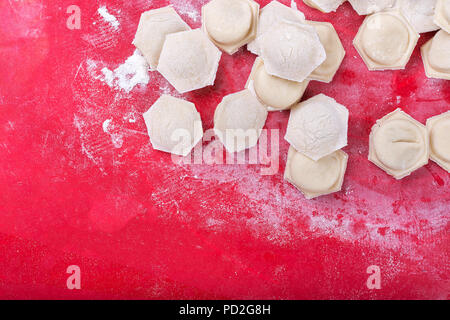 raw homemade dumplings with minced pork on the red surface. Stock Photo
