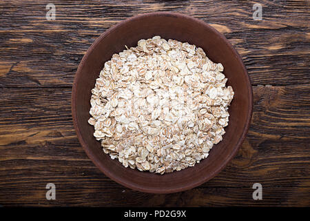 earthenware dish with raw oatmeal on a brown wooden table Stock Photo