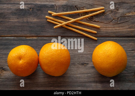 Oranges and bread sticks on a wooden board Stock Photo