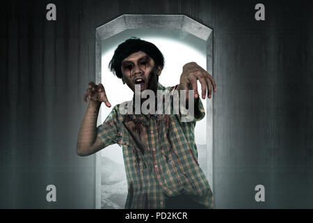 Scary zombie man coming from creepy place. Halloween concept Stock Photo