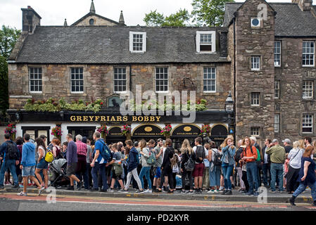 A walking tour stops at Greyfriars Bobby statue and public house, blocking the pavement and forcing pedestrians to walk on the road. Stock Photo
