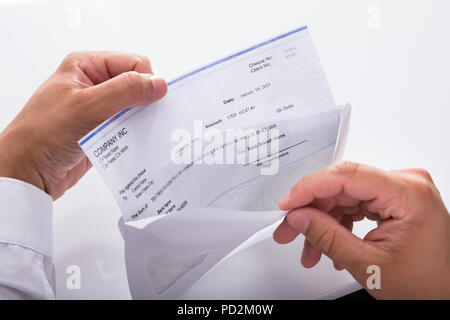 Close-up of a businessman's hand opening envelope with paycheck Stock Photo