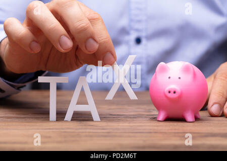 Human Hand Picking S Alphabet From Tax Word Beside Piggybank Stock Photo