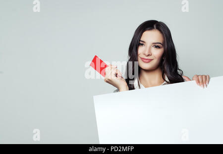 Smiling business woman showing red empty card and holding white blank banner backround. Business, advertising marketing and product placement concept Stock Photo