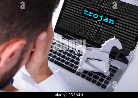 Businessman With Laptop Screen Showing Trojan Text With Binary Digits Stock Photo