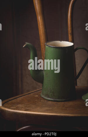 Still life of antique green kettle on the chair over vintage background Stock Photo