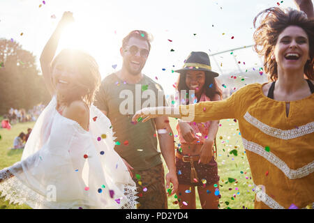 Young adult friends throwing and dancing in confetti at Holi Festival Stock Photo