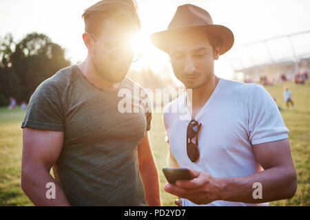 Two young men looking at smartphone at Holi Festival, detail of feet Stock Photo
