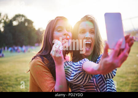 Two young woman covered in coloured chalk powder taking selfie at Holi Festival Stock Photo