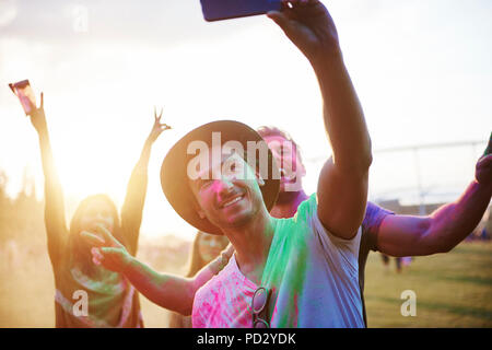 Four young adult friends covered in coloured chalk powder taking selfie at Holi Festival Stock Photo