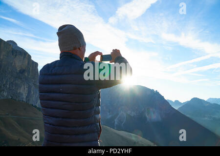 Hiker photographing of view of sunrise, Canazei, Trentino-Alto Adige, Italy Stock Photo