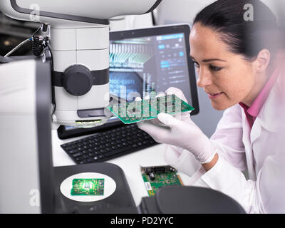 Engineer using 3D servo microscope to view dimensional accuracy of manufactured PCB assembly Stock Photo