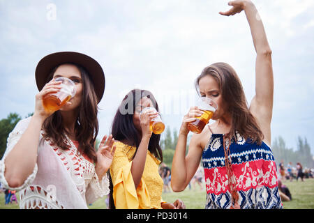 Friends drinking and dancing with arms raised in music festival Stock Photo