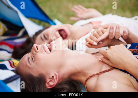 Friends lying on ground, laughing and enjoying music festival Stock Photo