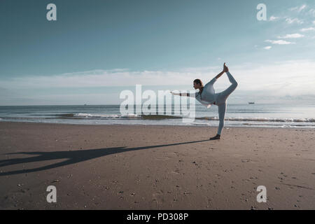 Woman practising yoga on beach Stock Photo