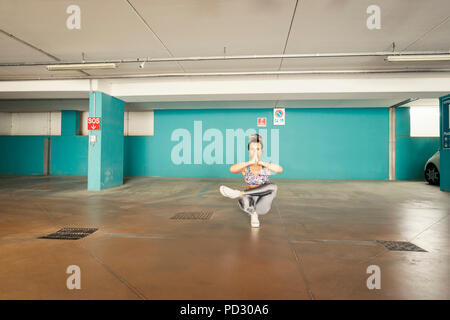 Woman practising yoga in parking lot Stock Photo
